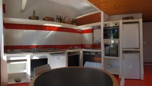 A compact kitchen with white cabinets, a built-in oven, and a refrigerator. - Ruby Apartment 3 (Sanremo)