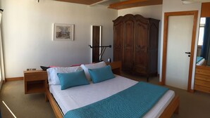 A bedroom with a large bed, wooden wardrobe, and a bedside table. - Ruby Apartment 3 (Sanremo)