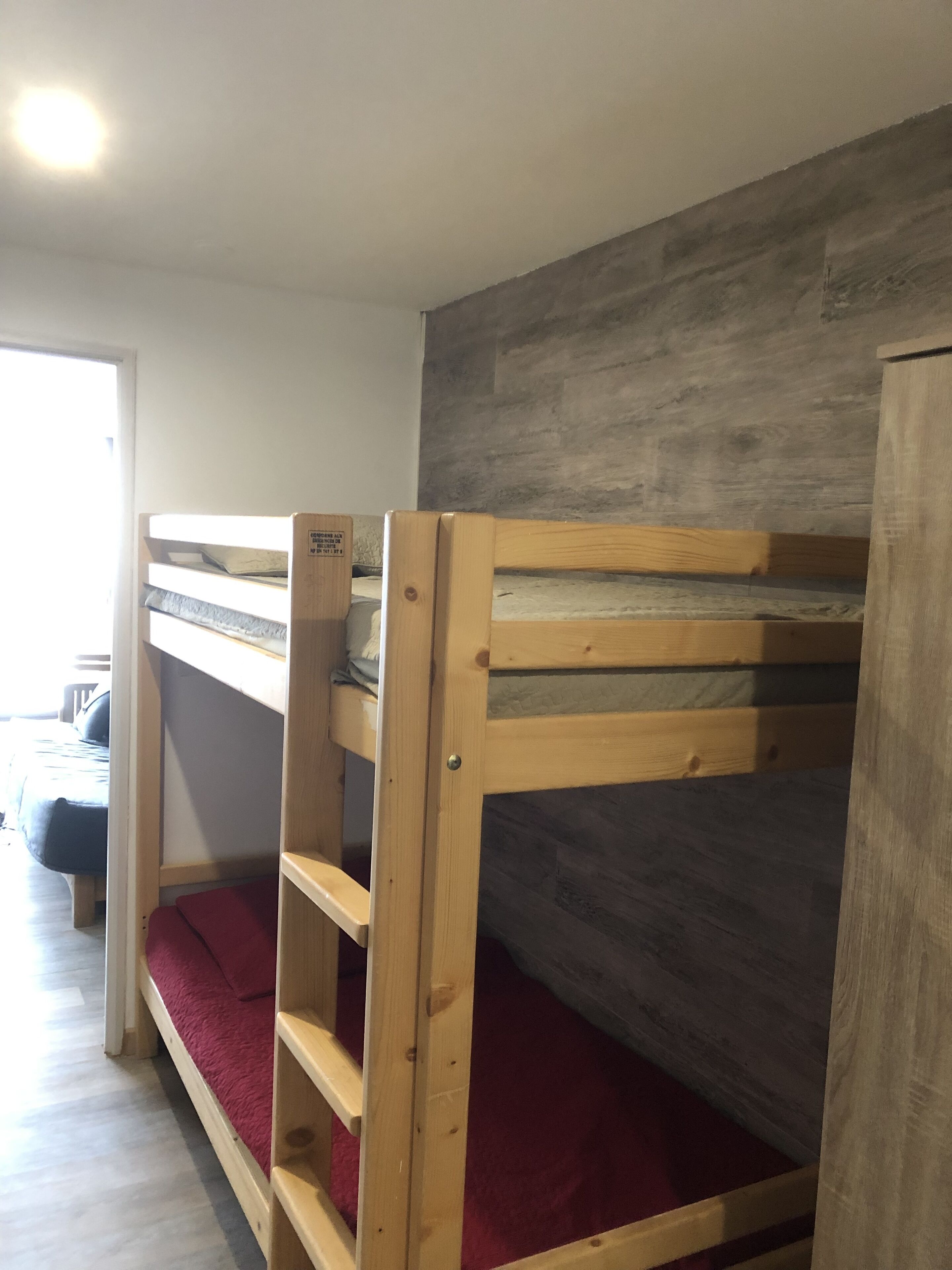 Camera con letto a castello, parete grigia e porta in legno.