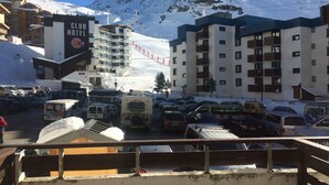 A hotel with multiple floors, a ski lift in the background, and a parking lot filled with vehicles.