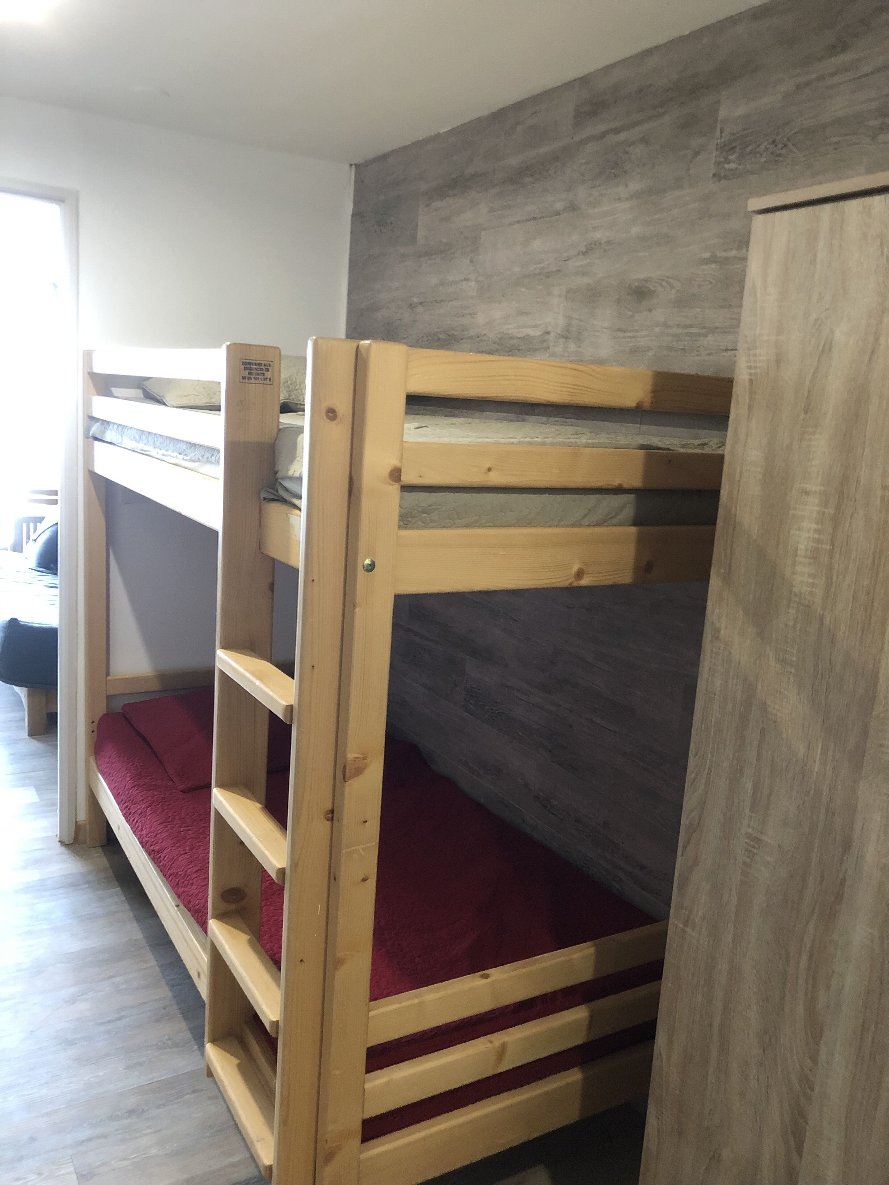 Dormitorio con literas, pared gris y armario de madera.