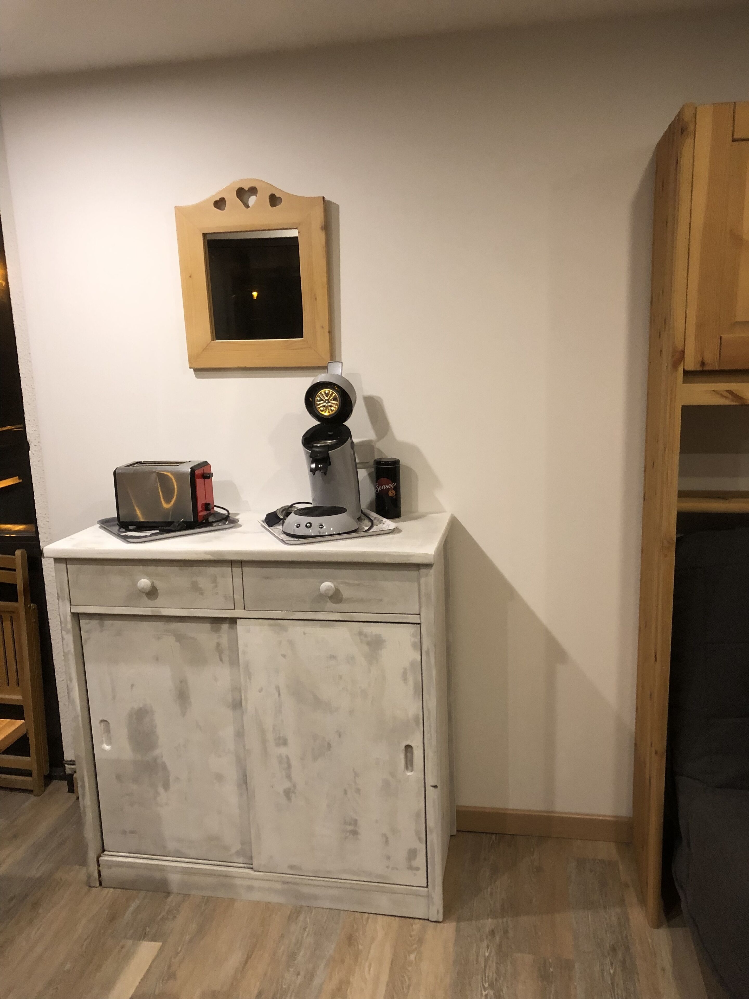 A kitchenette with a coffee maker, toaster, and a framed picture on the wall.