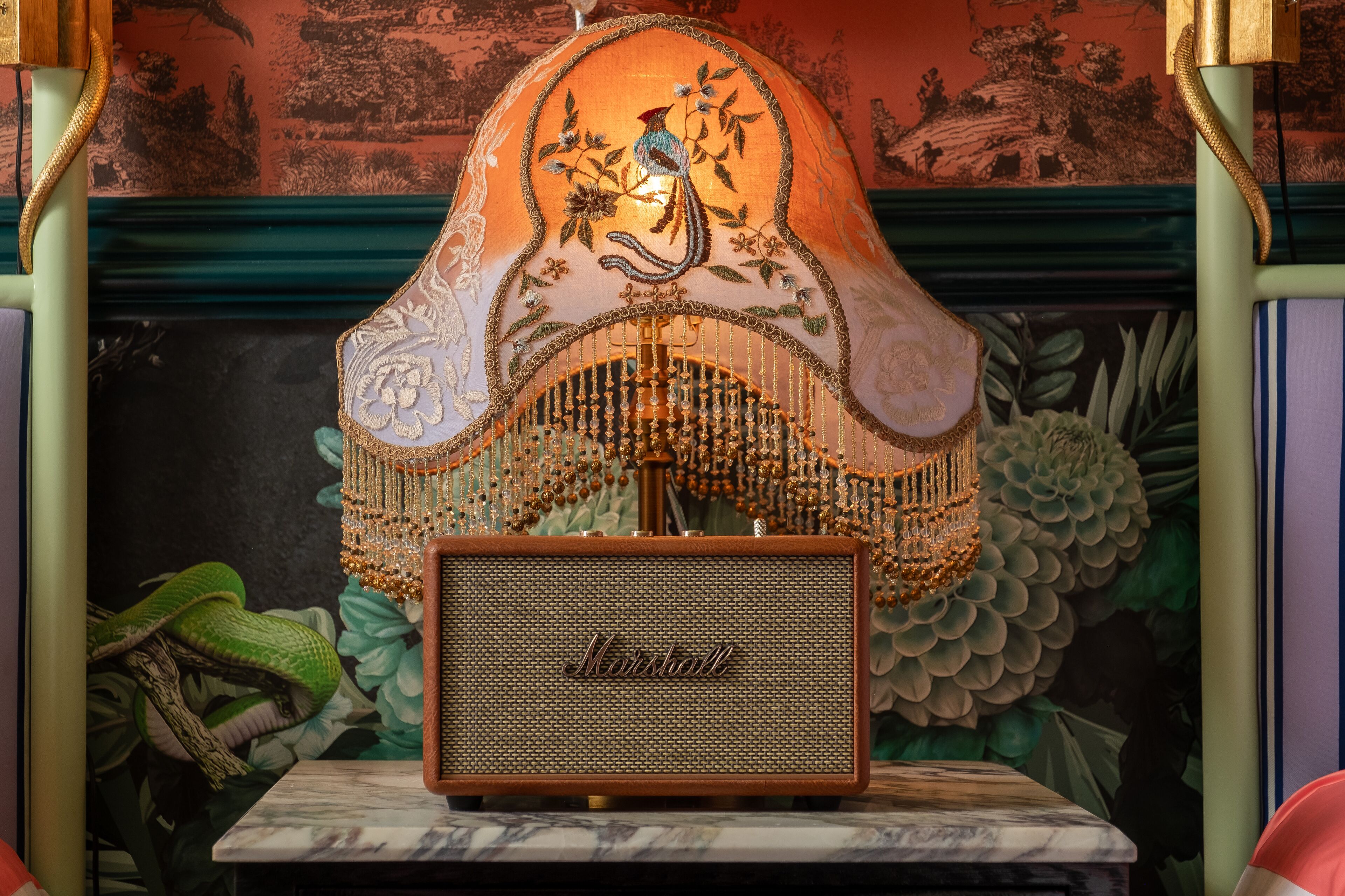 A vintage Marshall amplifier on a marble table with a decorative lamp behind it.