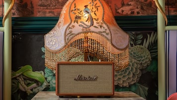 A vintage Marshall amplifier on a marble table with a decorative lamp behind it.