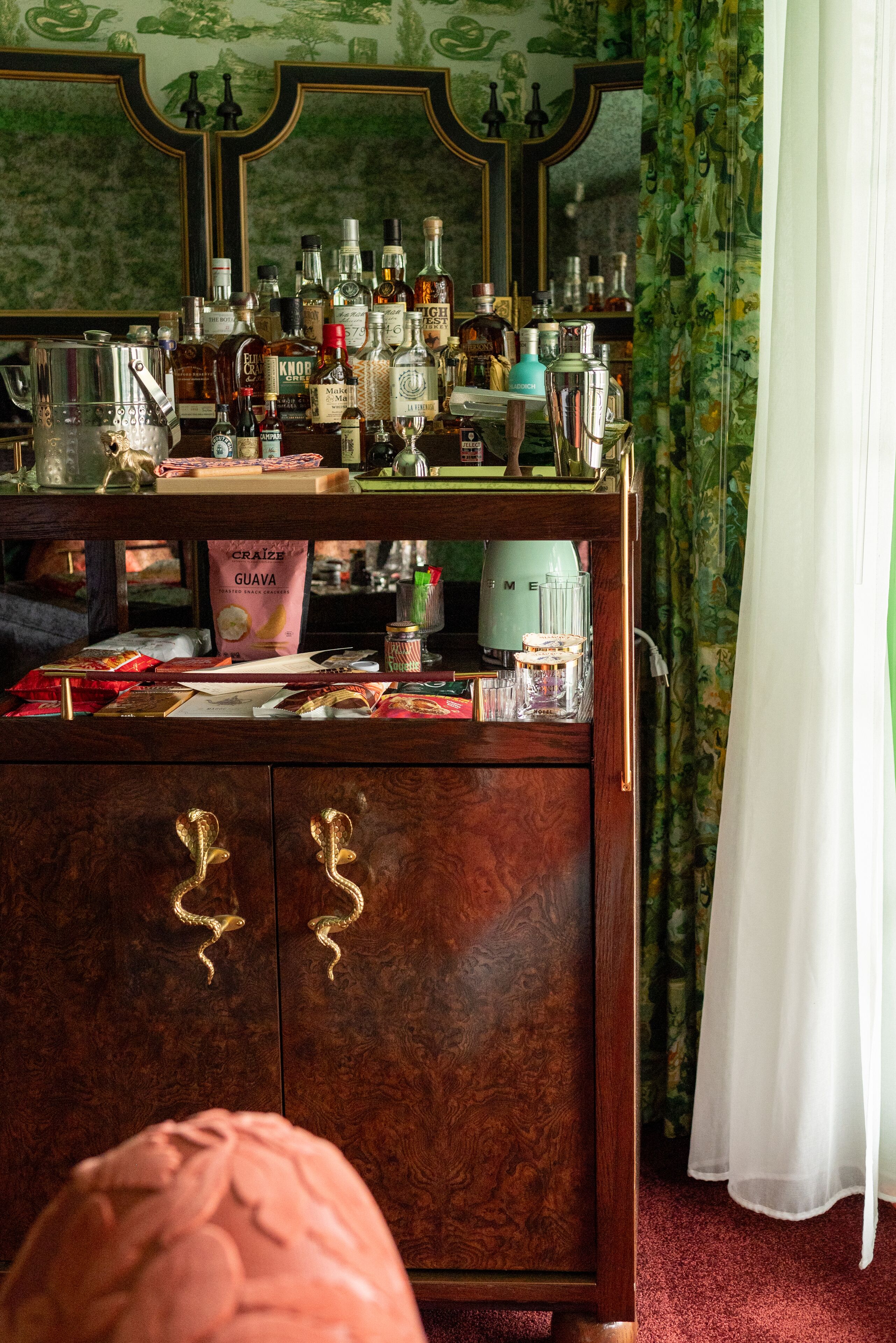 Uma área de bar com um armário de madeira, garrafas e um espelho.