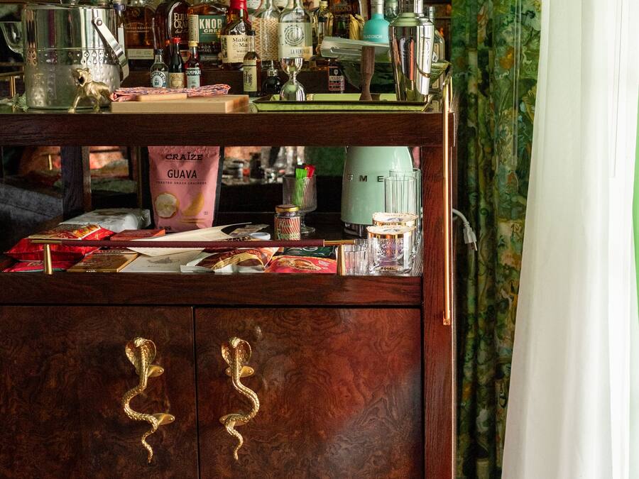 Uma área de bar com um armário de madeira, garrafas e um espelho.