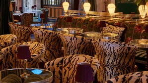 A luxurious interior with a large chandelier, patterned sofas, and a view of a cityscape through a large window. - Lafayette Hotel & Club (San Diego)