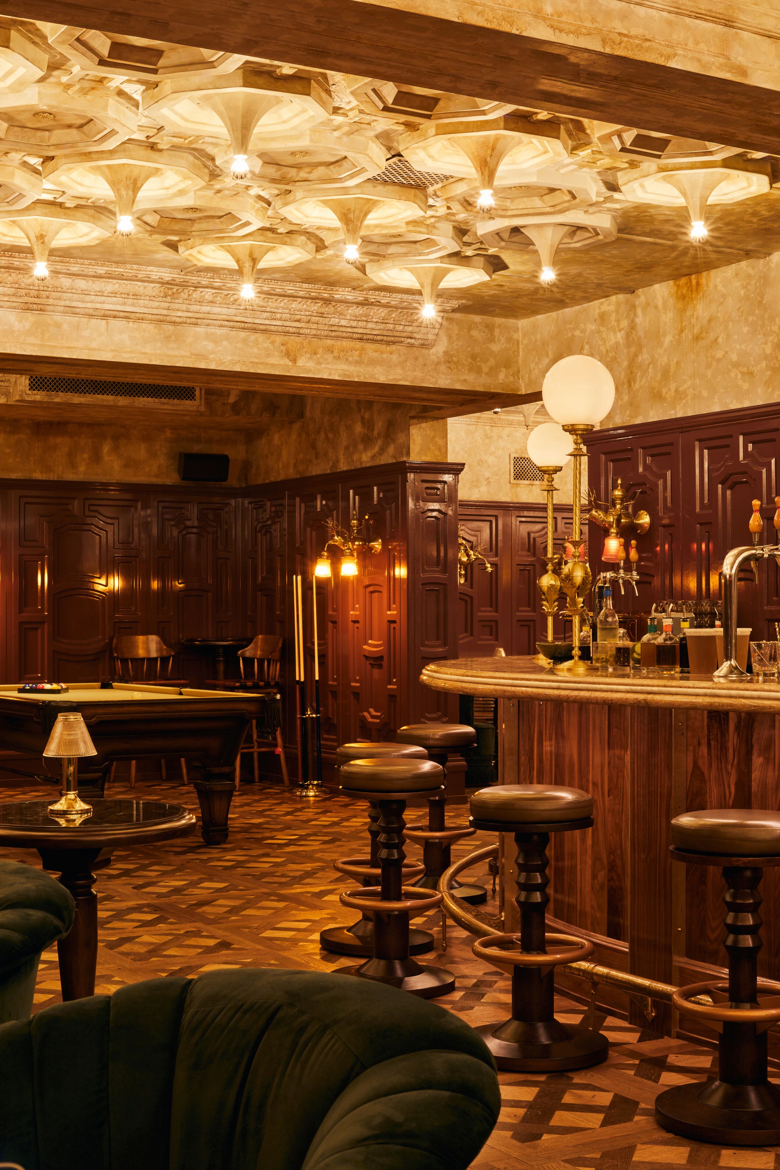 A bar area with wooden furniture, a pool table, and a bar counter with stools.
