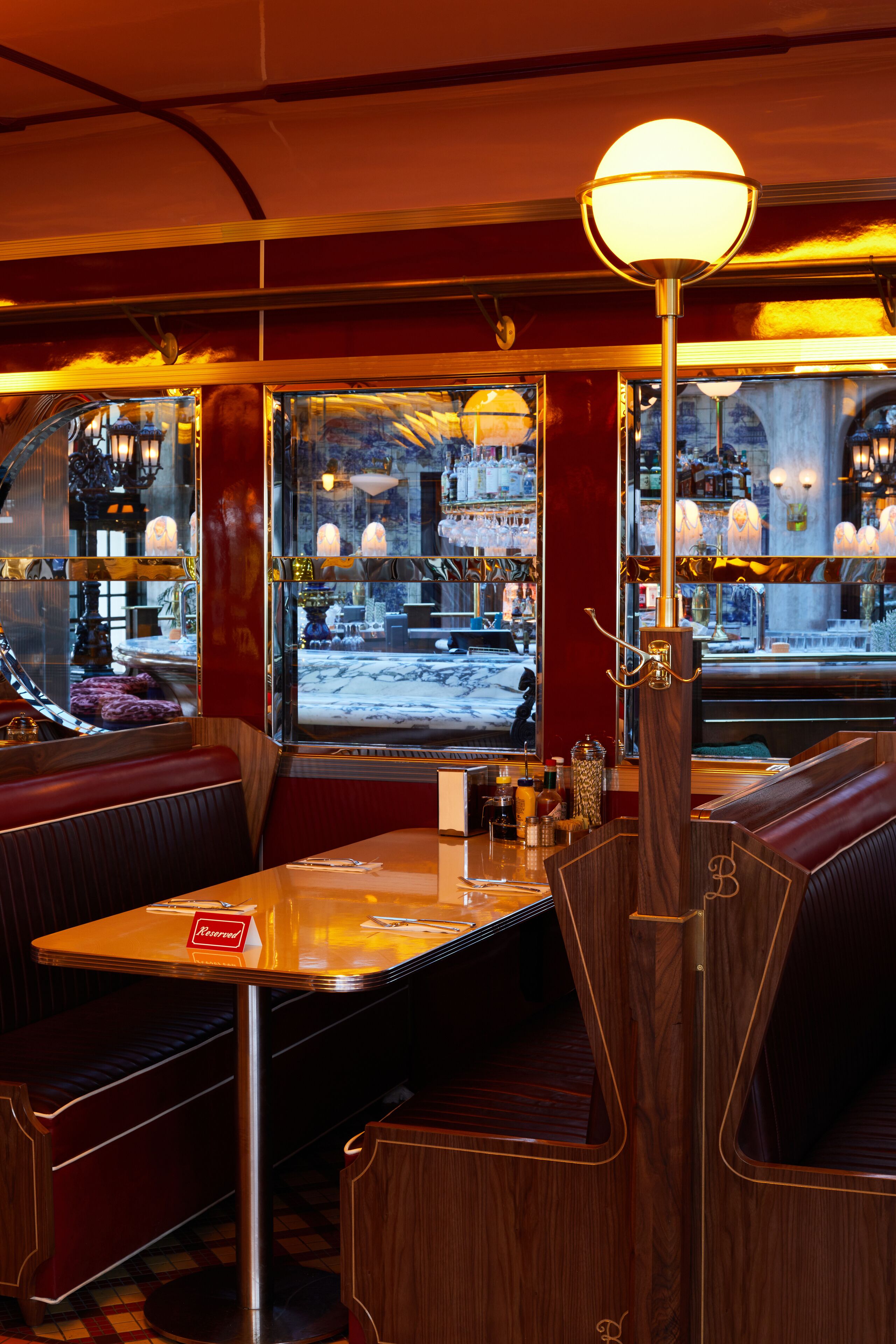 Un restaurant amb seients de fusta, una zona de bar i un gran finestral amb vista al carrer.