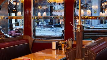 Un restaurant amb seients de fusta, una zona de bar i un gran finestral amb vista al carrer.