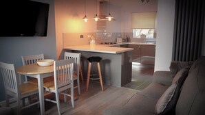 Una cucina moderna con zona pranzo, uno sgabello da bar e un divano.
