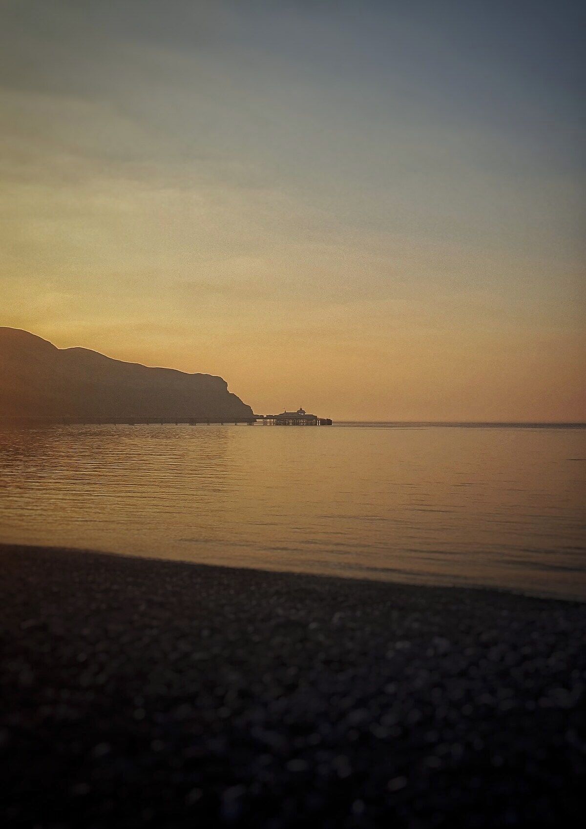 Une étendue d’eau calme, avec une rive éloignée et une construction sur la rive opposée.