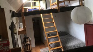 A dormitory room with bunk beds, a ladder, a desk with a chair, and a red cabinet. - Bellchassagne: house  - 2 rooms - 2/3 persons (Bellechassagne)