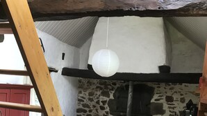 A rustic interior with a wooden staircase, a stone wall, a tiled floor, a red table with chairs, and a small refrigerator. - Bellchassagne: house  - 2 rooms - 2/3 persons (Bellechassagne)