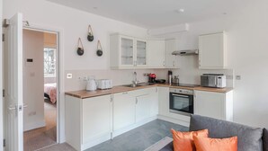 Una cocina compacta con armarios blancos, microondas, tostadora y un lavabo.