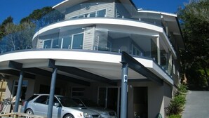 Una casa moderna de varios pisos con diseño curvo, ventanas grandes y un camino de entrada cubierto.