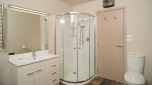 Un baño moderno con ducha acristalada, lavabo blanco y retrete.