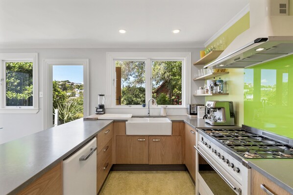 A modern kitchen with a large island, a built-in oven, and a view of greenery outside. - Stay near the City - Wellington Brooklyn Villa (Wellington CBD)