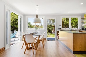 A modern kitchen with a dining area, large windows, and a view of the outdoors. - Stay near the City - Wellington Brooklyn Villa (Wellington CBD)