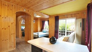 Ein Holzblockhaus im Inneren mit einem Bett, einem Esstisch und einer Küchenzeile.