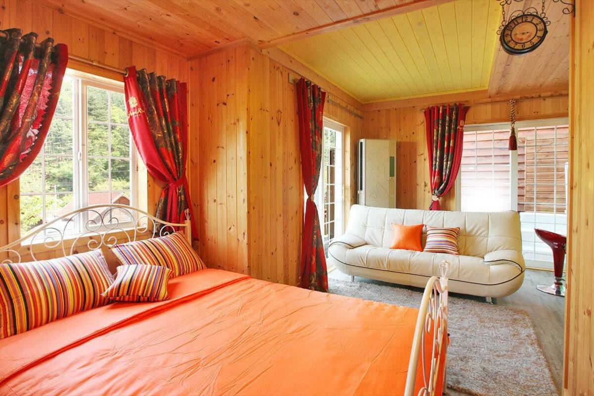 Una habitación de cabaña de madera con una cama, un sofá blanco y cortinas.