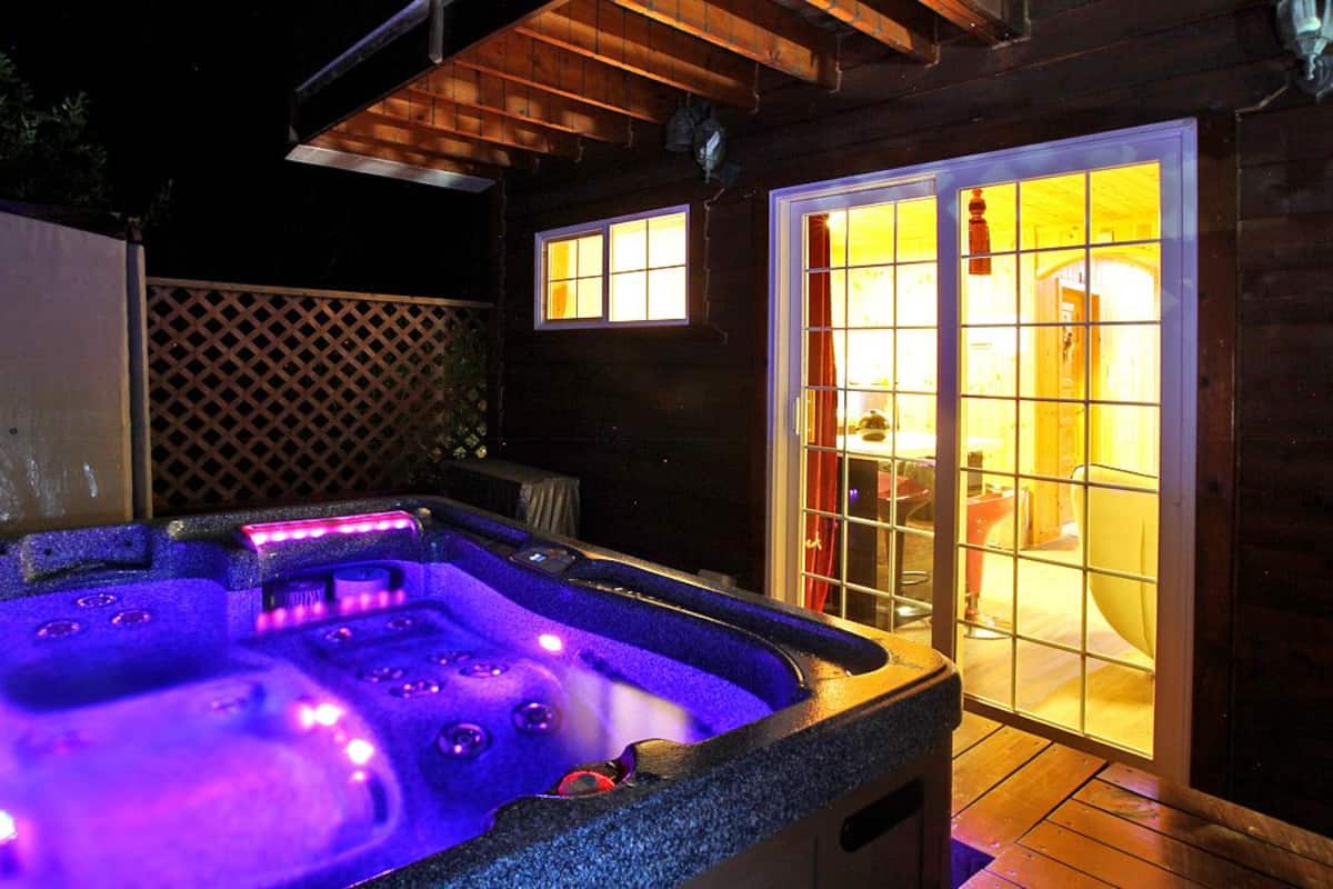 Un jacuzzi con terraza de madera y un área de patio techada.