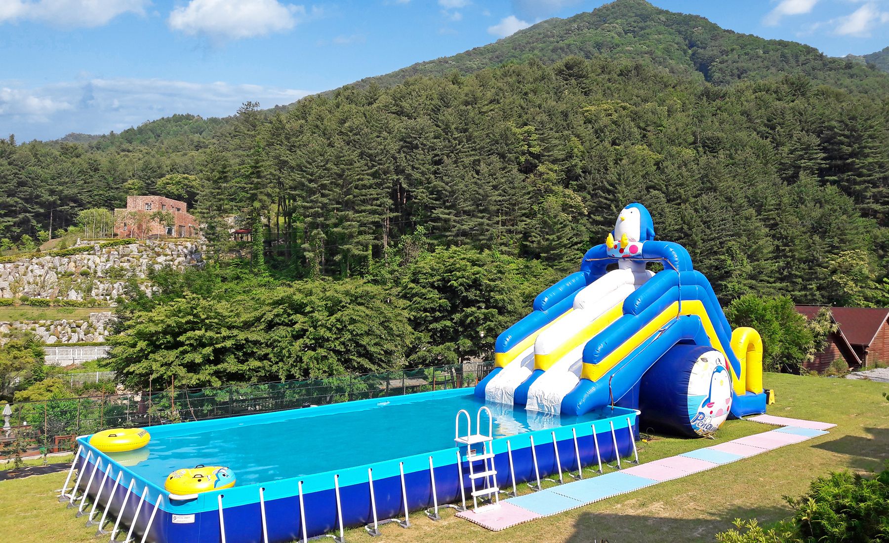 A swimming pool with inflatable slides and a small inflatable pool.