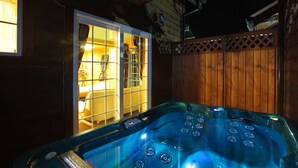 Ein Whirlpool in einer Holzhütte mit Blick auf einen Raum durch eine Glastür.