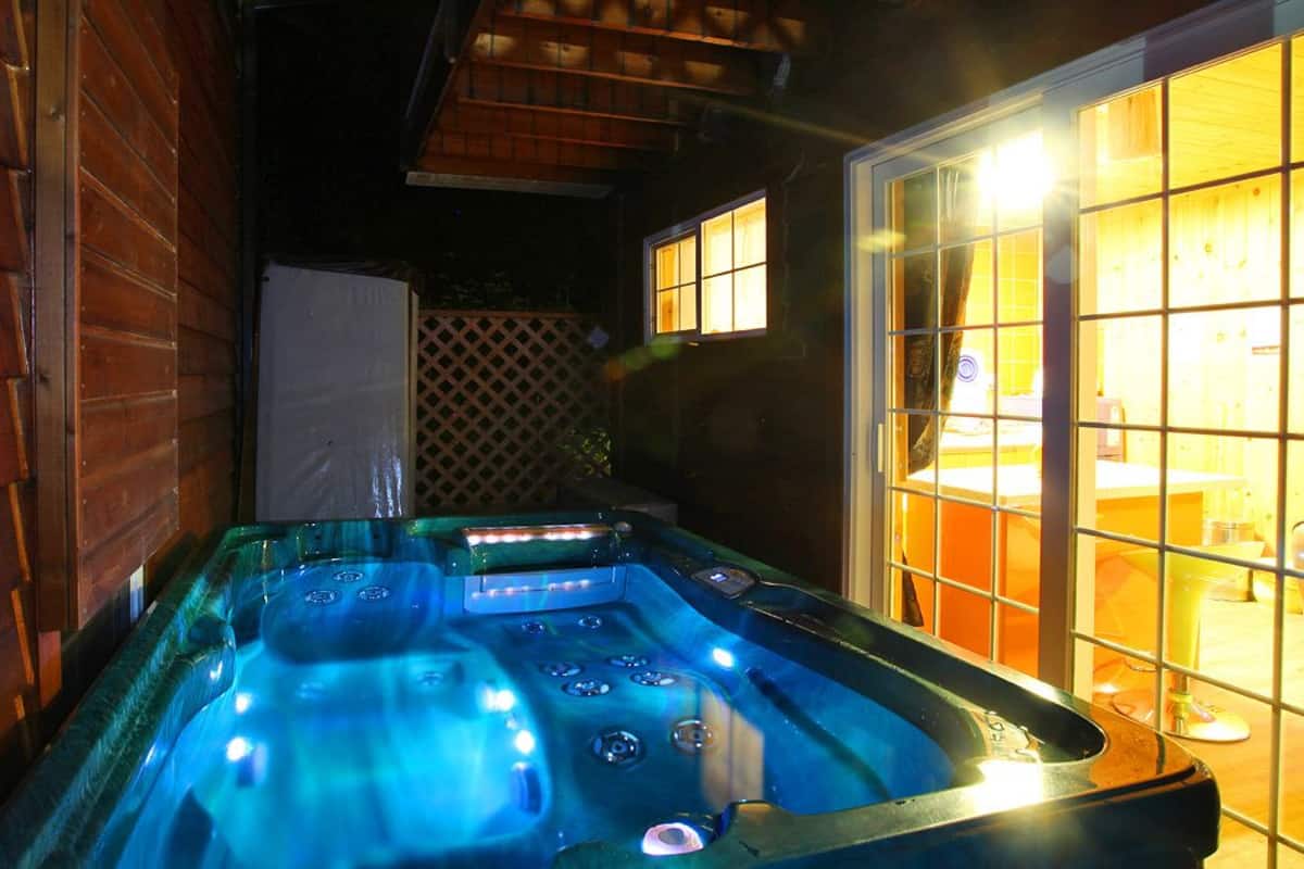 Un jacuzzi con revestimiento de madera y puertas de vidrio, iluminado con una luz cálida.