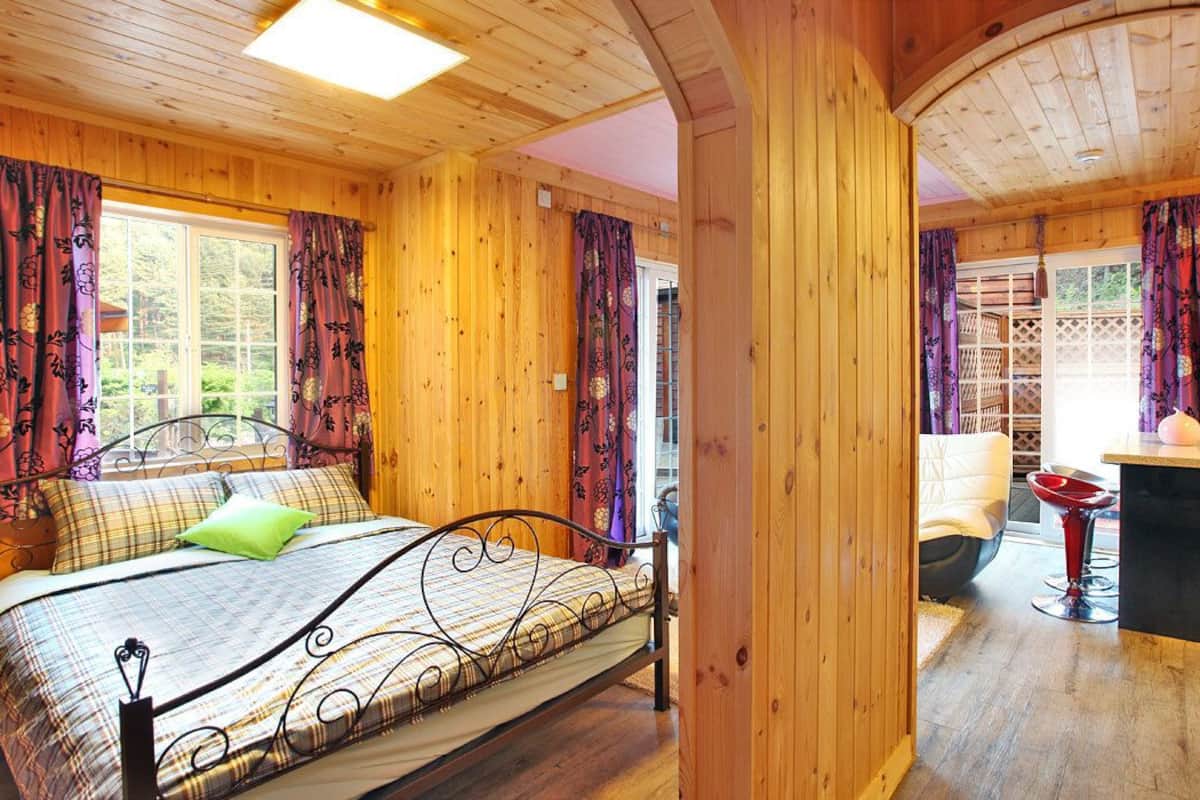 Interior de una cabaña de madera con una cama, un escritorio y una silla.