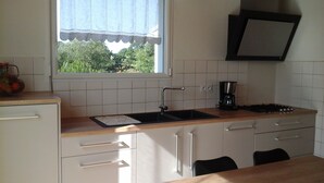 A kitchen with a window, sink, stove, and cabinets. - House with large terrace and fenced garden (Saint-Philibert)