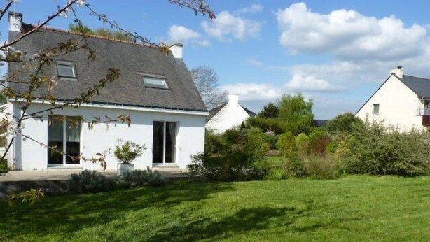 A white house with a sloped roof, a small front porch, and a well-maintained lawn. - House with large terrace and fenced garden (Saint-Philibert)