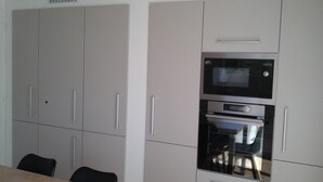 A kitchen with white cabinets, a microwave, and an oven. - House with large terrace and fenced garden (Saint-Philibert)