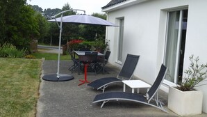 An outdoor patio with a table and chairs, a sun umbrella, and a potted plant. - House with large terrace and fenced garden (Saint-Philibert)