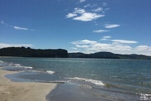 A beach with clear water, a sandy shore, and distant hills. - CooksEstuaryEscape-Waterfront at your doorstep (Price enquire for small groups) (Cooks Beach)