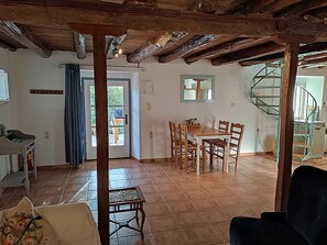 A spacious dining area with a wooden table and chairs, a staircase, and a view of the outdoors. - Stylish Stone Cottage with Pool near Fiskardo (Agrilias)