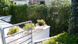 Un jardin sur le toit, agrémenté de plantes en pot et doté d’une rambarde en métal.
