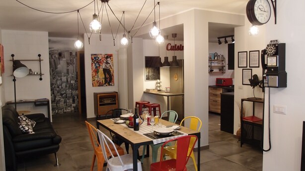Une cuisine moderne avec un coin repas, comprenant une table en bois, des chaises colorées et un réfrigérateur rouge.