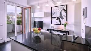A modern kitchen with a black granite countertop, a built-in oven, and a large window overlooking a balcony.