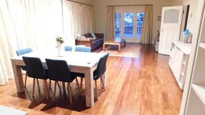 Un vaste espace de vie doté d’un plancher en bois, d’une table à manger avec des chaises, d’un canapé et d’une table basse.