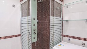 A bathroom with a shower enclosure, a sink, and a toilet.