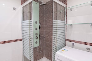A bathroom with a shower enclosure, a sink, and a toilet.