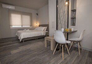 A modern bedroom with a bed, bedside table, and a desk with chairs. - Homelike Studios in the Heart of the City by GHH (Athens)