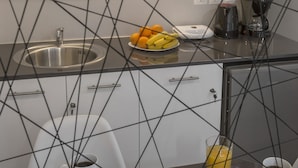 Una cocina moderna con un lavamanos de acero inoxidable, una cafetera y un frutero sobre la encimera.
