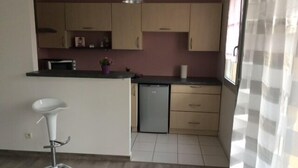 A kitchen with wooden cabinets, a white countertop, a sink, and a bar stool.