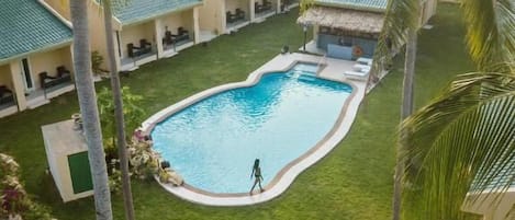 Una piscina rodeada de palmeras y un edificio con techo verde.