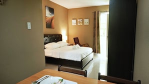 A hotel room with a neatly made bed, a dining table set with plates, cutlery, and glasses, and a chair. - Cococabana Panglao (Panglao)