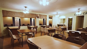 A dining area with multiple tables and chairs, wooden floors, and a ceiling with light fixtures. - Cococabana Panglao (Panglao)