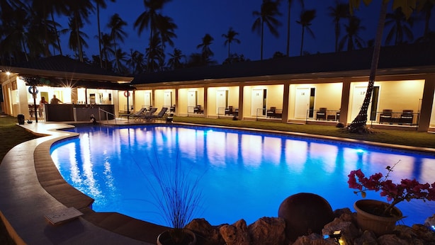 A poolside area with lounge chairs, a bar, and a building with numbered doors. - Cococabana Panglao (Panglao)