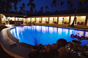 A poolside area with lounge chairs, a bar, and a building with numbered doors. - Cococabana Panglao (Panglao)